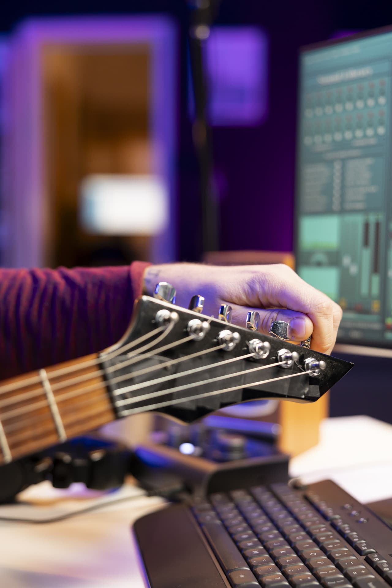 Musician tuning acoustic guitar strings before recording