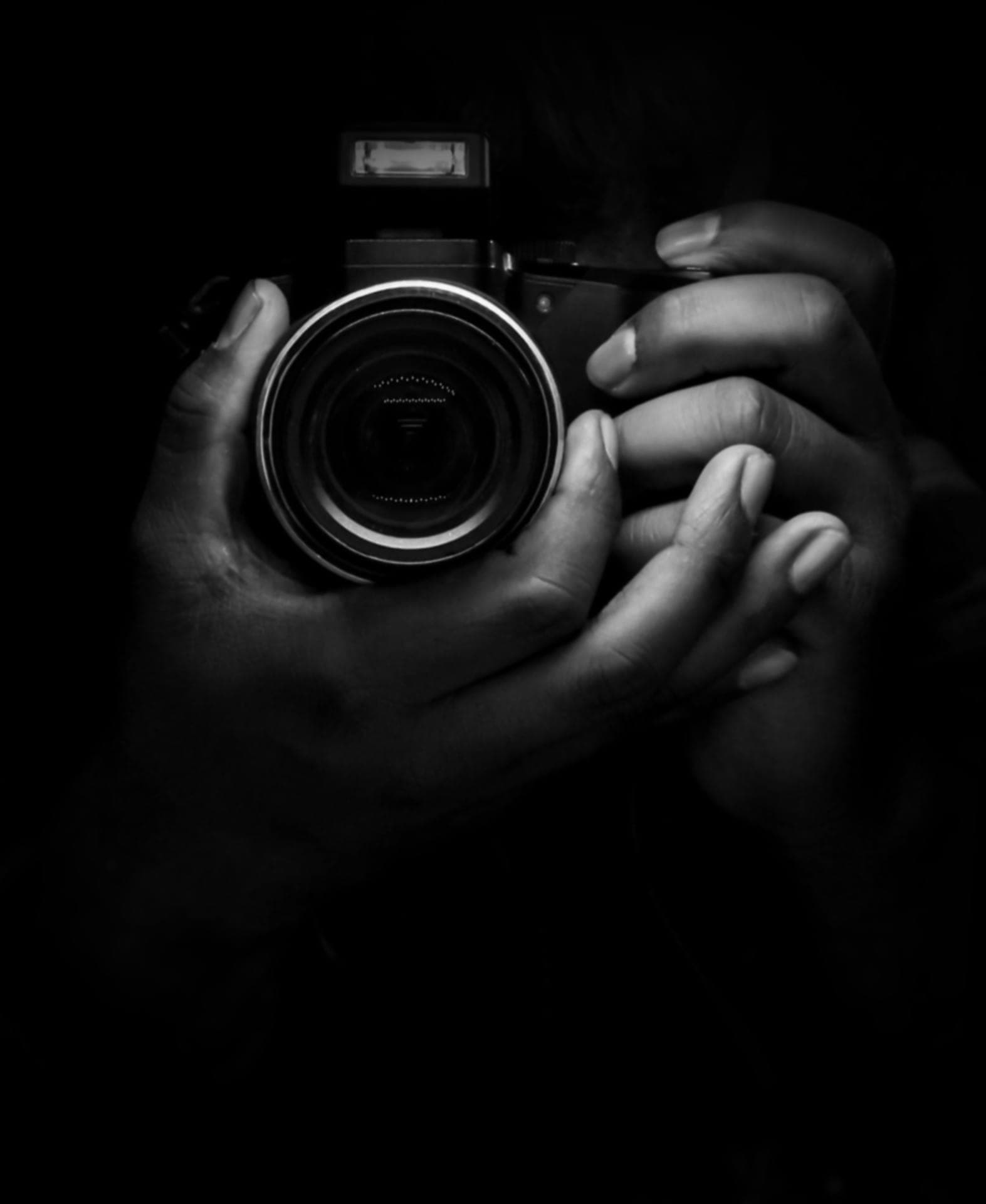 Hands holding a camera against a black background