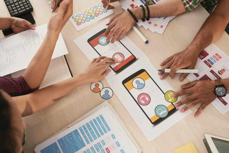 Creative team analyzing social media analytics on multiple devices with colorful brand strategy charts and algorithm performance graphs displayed on screens ALT Text: Marketing team reviewing social media algorithm performance data to fix engagement issues for brand growth